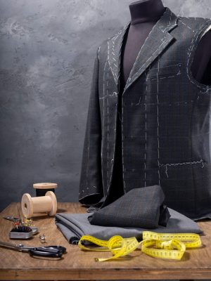 suit jacket on male tailor mannequin and sewing accessories, creative concept of clothes atelier